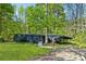 Exterior view of the home with a wooded lot, metal carport and front porch at 3541 Hutcheson Ferry Rd, Whitesburg, GA 30185