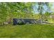 Exterior view of the home with a large grass lawn and wooded lot at 3541 Hutcheson Ferry Rd, Whitesburg, GA 30185