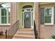 Detailed shot of the brick home's front entrance featuring a dark painted door, sidelights, and black metal railings at 2060 Pate Ridge Dr, Loganville, GA 30052