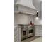 Gourmet kitchen with Wolf range, custom hood, white cabinets, gold hardware, and white subway tile backsplash at 2305 Whiting Bay Cts, Kennesaw, GA 30152