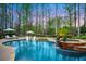 Backyard pool area with stone accents, lush trees and outdoor seating at 2305 Whiting Bay Cts, Kennesaw, GA 30152