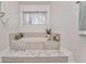 A modern soaking tub with tile surround sits beneath a bright window at 825 Clarion Way, Lawrenceville, GA 30044