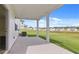 Covered patio with white pillars, concrete flooring, and a sprawling green lawn with houses in the distance at 1119 Blue Juniper Circle, Loganville, GA 30052