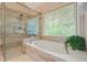 Bright bathroom featuring a soaking tub under a window and a glass-enclosed shower with beige tiling at 3130 Crestmont Nw Way, Kennesaw, GA 30152