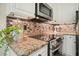 Close-up of kitchen featuring granite countertops, backsplash, and stainless steel oven at 3130 Crestmont Nw Way, Kennesaw, GA 30152