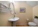 Small bathroom with pedestal sink, oval mirror, decorative shelving and beach themed art at 5556 Cascade Sw Run, Atlanta, GA 30336