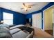 This bedroom has blue walls, neutral carpet, a ceiling fan, and closet, and a gray couch for relaxing at 5556 Cascade Sw Run, Atlanta, GA 30336