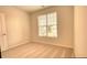 Sunlit bedroom with neutral carpet and paint, and a bright window at 711 Park Place Way, Social Circle, GA 30025