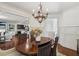 Cozy dining room featuring hardwood floors, a stylish chandelier, and an open view to the kitchen at 8385 E Village School E Dr, Cumming, GA 30041