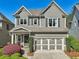 Charming two-story home with gray siding, stone accents, a two-car garage, and professional landscaping at 8385 E Village School E Dr, Cumming, GA 30041