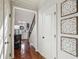 Hallway with hardwood floors, decorative wall art, and staircase view at 8385 E Village School E Dr, Cumming, GA 30041