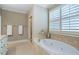 Main bathroom showcasing a large soaking tub, tiled walls, glass shower, and a window with plantation shutters at 1127 Bank Se St, Smyrna, GA 30080