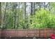 A wooded backyard is enclosed by a wooden fence with mature trees for privacy and shade at 307 Downing Creek Trl, Canton, GA 30114