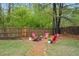 A backyard with a gravel area featuring red Adirondack chairs around a fire pit, perfect for outdoor gatherings at 307 Downing Creek Trl, Canton, GA 30114