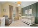 A charming Bedroom features a white crib, a cozy gray armchair, and warm, inviting decor at 307 Downing Creek Trl, Canton, GA 30114