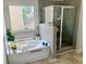Bright bathroom featuring a tub with tile surround and a glass-enclosed shower at 5243 Cantbury Way, Atlanta, GA 30349