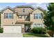 Charming two-story home with a tan exterior, a two-car garage, shuttered windows, and well-maintained landscaping at 5243 Cantbury Way, Atlanta, GA 30349