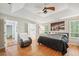 Comfortable bedroom featuring hardwood floors, tray ceilings, fan and adjacent bathroom access at 642 Towering Pine Trl, Lawrenceville, GA 30045