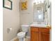 This half bathroom features a wood vanity with a sink, toilet, and decorative wall art at 726 Fir Chase, Fairburn, GA 30213