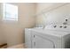 Bright laundry room with white washer and dryer, wire shelving, and a window at 726 Fir Chase, Fairburn, GA 30213