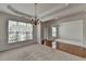 Elegant dining room with chair rail, tray ceiling, and chandelier. View into adjacent room at 580 Hammersmith Dr, Suwanee, GA 30024