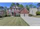 Charming two-story brick home with a well-manicured lawn and two-car garage on a sunny day at 580 Hammersmith Dr, Suwanee, GA 30024