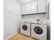 Laundry area with side by side, modern, white washer and dryer units plus overhead cabinets at 2470 Woodmere Dr, Marietta, GA 30068
