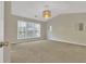 Spacious bedroom with neutral tones, carpet, three windows, and modern light fixture at 818 Prada Ct, Lawrenceville, GA 30043