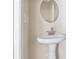Elegant pedestal sink beneath a round mirror gives this bathroom a clean, modern aesthetic at 121 Dunleith Sw Pkwy, Marietta, GA 30008