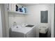 Bright laundry room featuring a white washer and dryer, a shelf, and white walls at 63 Fair Haven Se Way, Smyrna, GA 30080