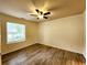 An empty bedroom featuring wood floors, tan walls, and natural light from the window at 645 Crossbridge Aly, Johns Creek, GA 30022