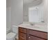 Bathroom featuring a sink with dark wood cabinets, toilet, and a large mirror with a partial view of the doorway at 8335 Village Pl, Suwanee, GA 30024