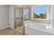 This luxurious bathroom features a garden tub, glass-enclosed shower and a picturesque window at 8335 Village Pl, Suwanee, GA 30024