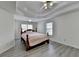 Spacious bedroom with gray wood floors, tray ceiling, ceiling fan, and windows with blinds at 2822 Savannah Walk Cv, Suwanee, GA 30024