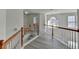 Upstairs hallway with natural light, hardwood floors, and classic wood railing at 2822 Savannah Walk Cv, Suwanee, GA 30024