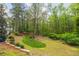 Expansive backyard with a lush lawn, a screened-in porch and vibrant azaleas creating a serene outdoor space at 1800 East Gate Dr, Smoke Rise, GA 30087