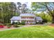 Inviting two-story home boasts a lush green lawn and a charming front porch in a serene setting at 1800 East Gate Dr, Smoke Rise, GA 30087