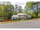 Lovely white two-story home with a double balcony, surrounded by mature trees and a green lawn at 1800 East Gate Dr, Smoke Rise, GA 30087