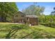View of a two-story home with a brick foundation and siding, surrounded by a lush green yard and mature trees at 4819 Elam Rd, Stone Mountain, GA 30083