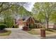 Traditional brick home featuring a manicured lawn, lush landscaping, and a circular driveway leading to a spacious two-car garage at 325 N Saint Phillip Ln, Alpharetta, GA 30022