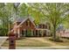 Beautiful two-story brick home with mature trees and a well-manicured lawn in a suburban neighborhood at 325 N Saint Phillip Ln, Alpharetta, GA 30022