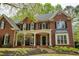 Attractive red brick home with a covered porch, steps to the front door and manicured landscaping at 325 N Saint Phillip Ln, Alpharetta, GA 30022