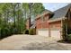 Elegant brick home with a two-car garage and an expansive concrete driveway, surrounded by lush landscaping at 325 N Saint Phillip Ln, Alpharetta, GA 30022