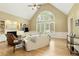 Bright living room boasts high vaulted ceilings, a large arched window, built-in shelves, and light hardwood flooring at 325 N Saint Phillip Ln, Alpharetta, GA 30022