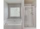 Bright bathroom featuring a soaking tub, framed window with blinds, and a glass-enclosed shower at 2045 Villa Spring Ct, Dacula, GA 30019