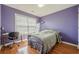 A bedroom with wood floors, a window with blinds, a desk, and a purple wall at 2470 Cordillo Dr, Dacula, GA 30019