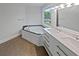 Bathroom with a double vanity, garden tub with a blue tiled backsplash, and a window at 2021 Emerald Dr, Loganville, GA 30052