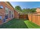 A fenced backyard features manicured artificial turf and backs to mature trees. Windows view backyard from inside the home at 132 Westchester Se Dr, Smyrna, GA 30082