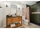 Bathroom boasts a wood vanity, black countertop, vessel sink, mirror, and green tiled shower at 78 Beverly Ne Rd, Atlanta, GA 30309