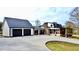 Side view features a two-car garage and screened porch, complemented by a stone chimney and lush landscape at 85 Carroll Slough Rd, Kingston, GA 30145